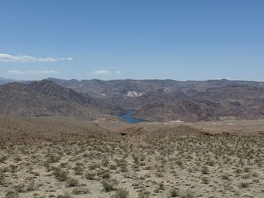 Un paysage désertique avec des montagnes et un lac au loin.