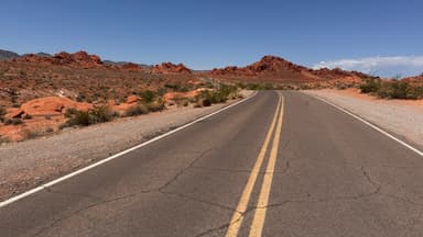 A winding road through red rock formations under a clear blue sky.